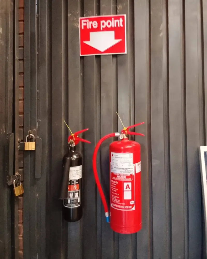 A CO2 extinguisher and a water extinguisher mounted under a Fire point sign