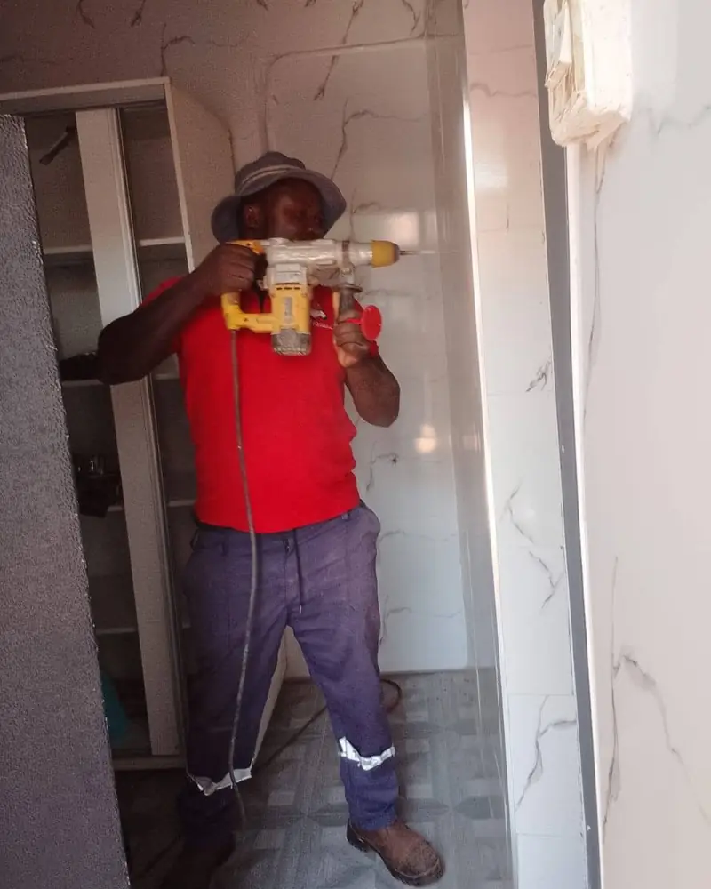 A technician drilling into a tiled wall during an installation