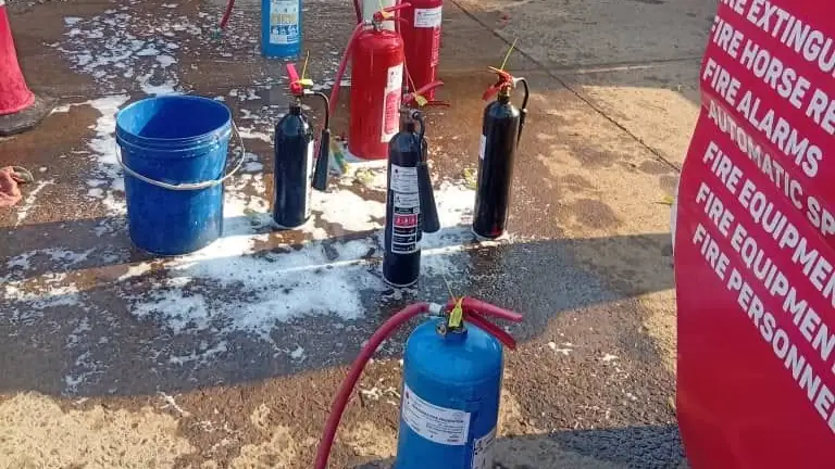 Extinguishers standing in a yard during servicing, next to the Makanaka van